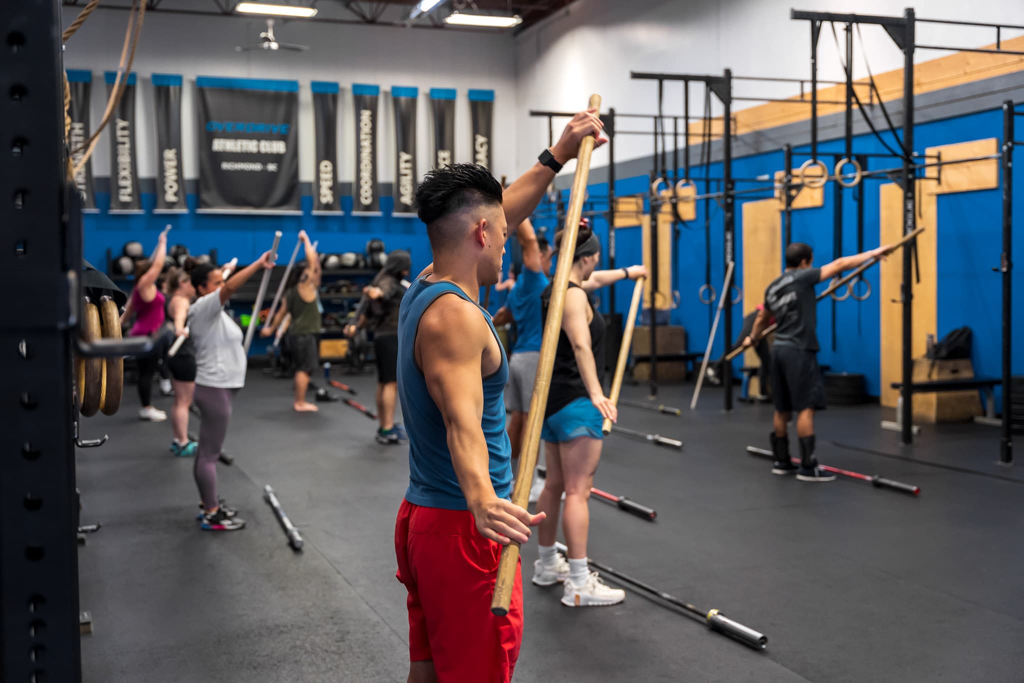 A member holding a training bar overhead during a technique drill at Overdrive Athletic Club in Richmond, BC