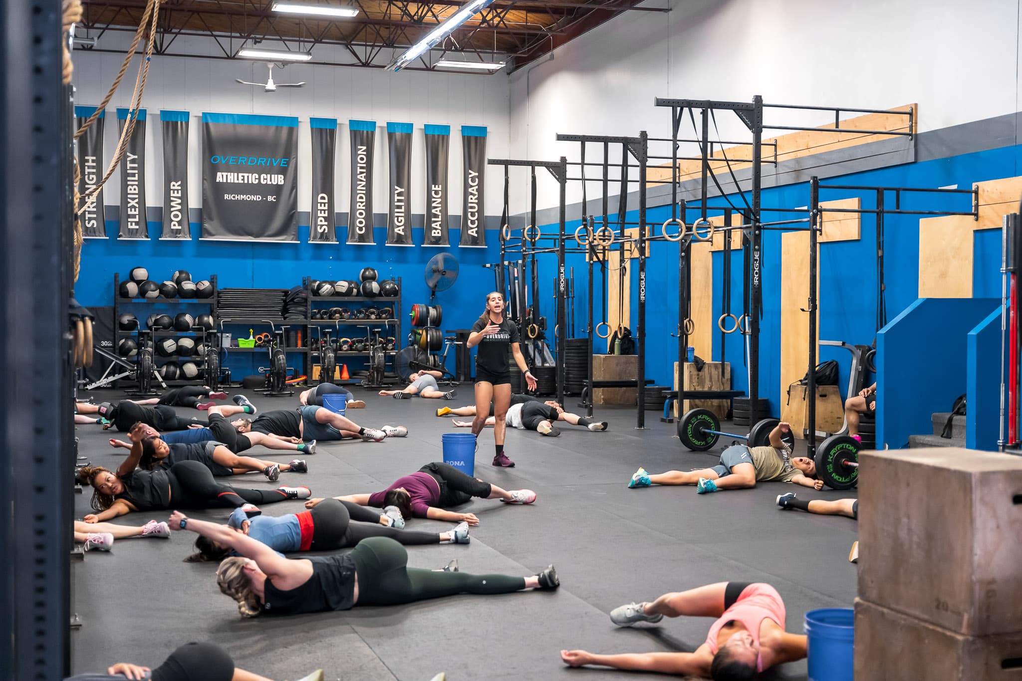 A coach instructing a group fitness class on the mats at Overdrive Athletic Club in Richmond, BC