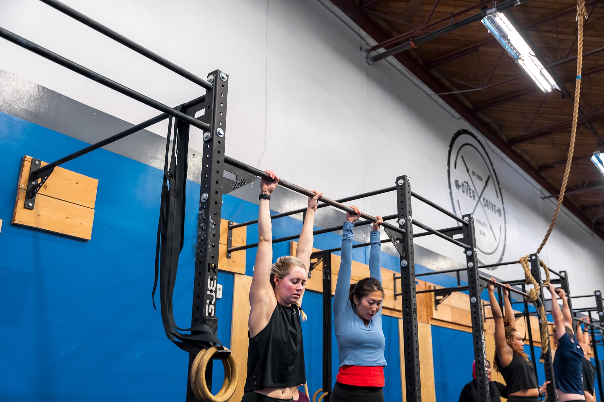 Members hanging from the pull-up bar beneath the Overdrive Athletic Club logo in Richmond, BC